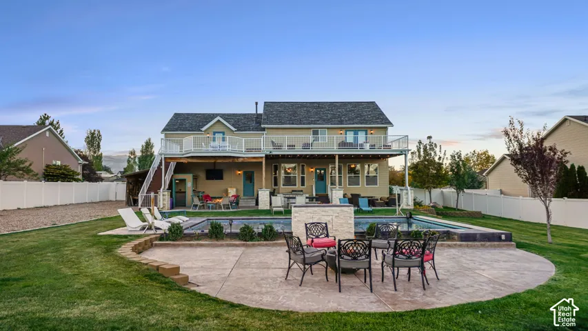 Expansive backyard featuring a large in-ground swimming pool, a multi-level stamped concrete patio, and a tiered deck with white railings