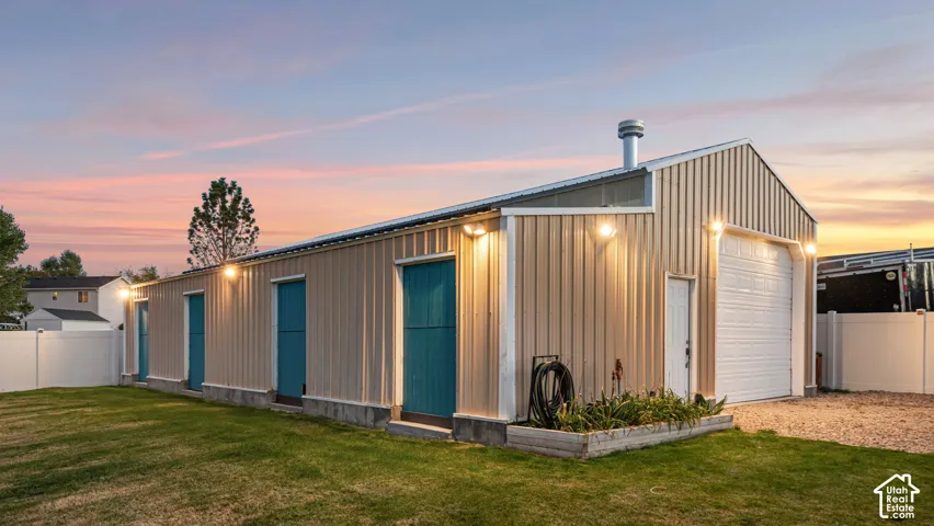 Metal-clad outbuilding featuring a pitched roof, multiple entry doors, and a large roll-up garage door