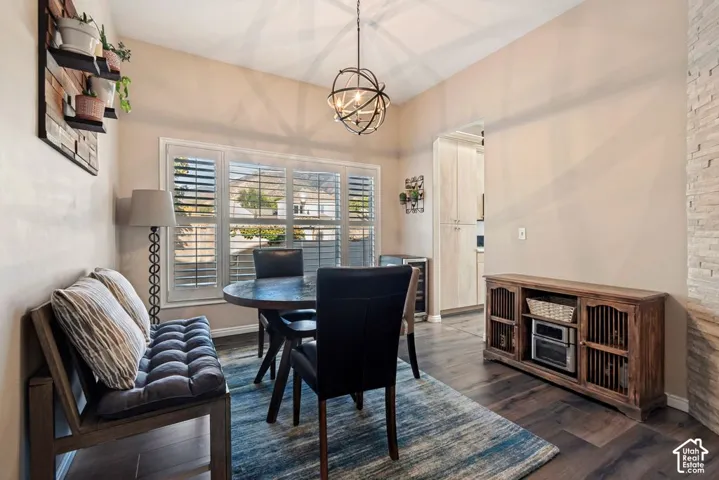 Vaulted ceiling with an orb chandelier, wood-finish flooring, and a stone-clad accent wall