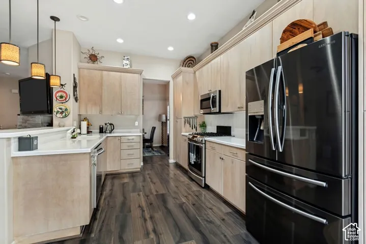 Wood-finish flooring, light-toned cabinetry, stainless steel appliances, recessed lighting, and pendant lighting