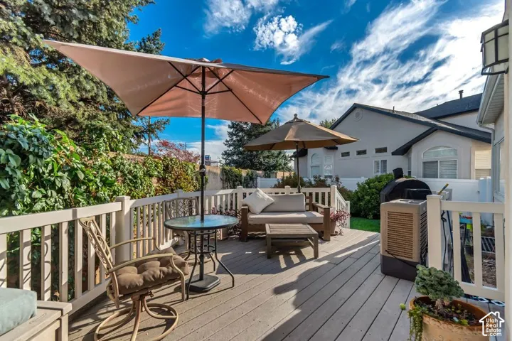 Expansive outdoor deck featuring wood-finish flooring, white railing, and mature landscaping