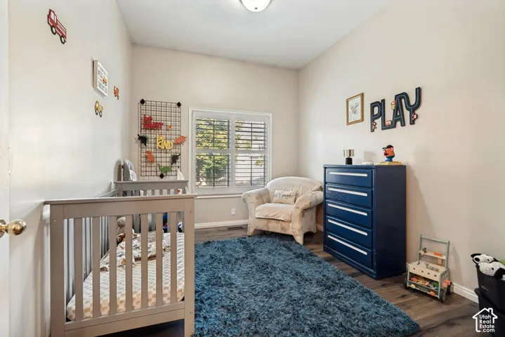 Vaulted ceiling, wood-finish flooring, white walls, and a window with white louvered shutters