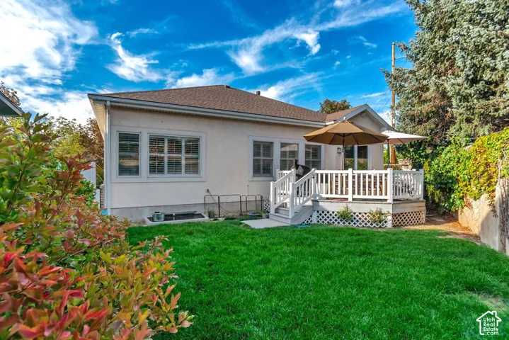 Expansive green lawn, white deck, white railing, mature landscaping, and an exterior with multiple windows