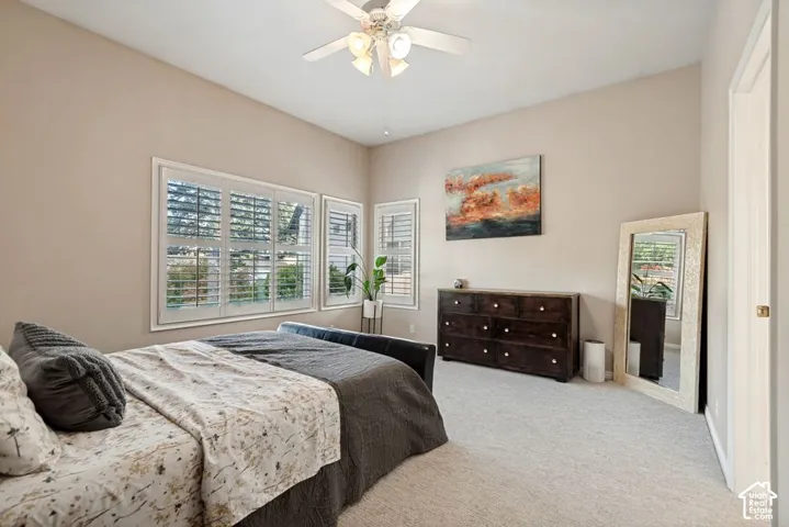 Recessed lighting, ceiling fan with light fixture, multiple windows with plantation shutters, and light-toned carpet flooring