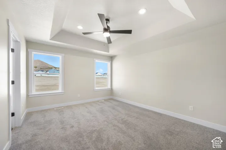 Tray ceiling with recessed lighting, ceiling fan, and two large windows