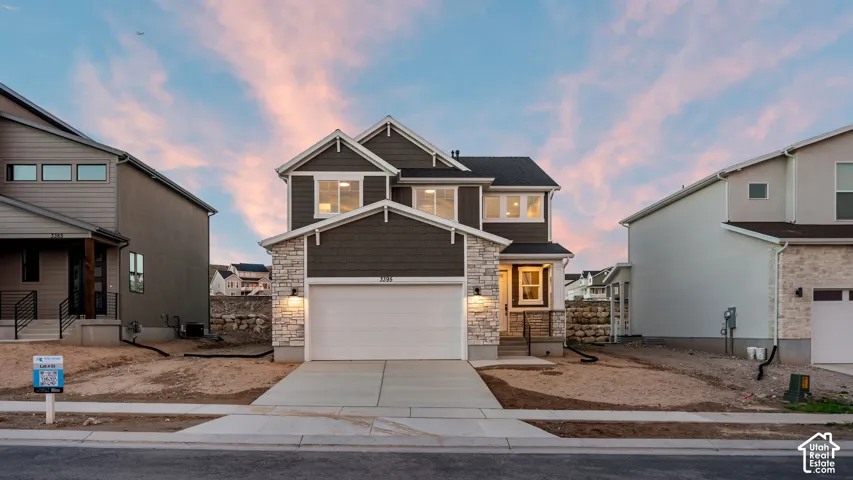 Two-story residence featuring a dark-toned siding facade, stone accents, a two-car garage, and a concrete driveway