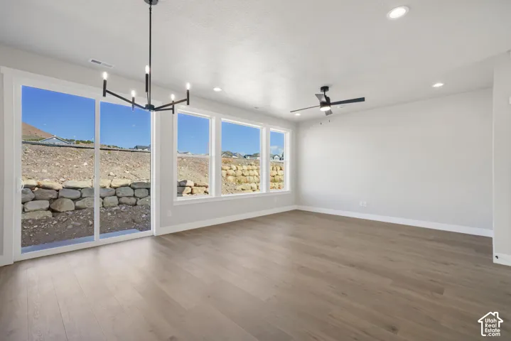 Spacious room featuring wood-finish flooring, a contemporary chandelier, recessed lighting, and a ceiling fan