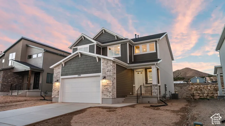 Two-story residence featuring a stone and siding exterior, an attached two-car garage, and a covered entry porch