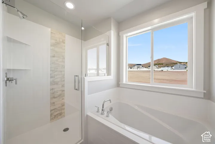 Walk-in shower with clear glass enclosure, integrated shelving, and a decorative tile accent