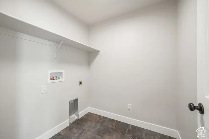 Laundry area with a built-in shelf, plumbing hookups, electrical outlets, and dark-toned flooring
