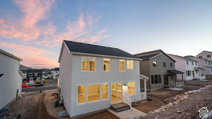 Two-story residence featuring a light-colored exterior, multiple large windows, and a covered patio with a white railing