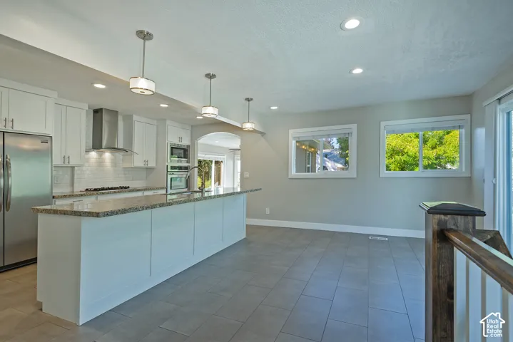 Contemporary kitchen with white cabinetry, stainless steel appliances, a large island with a stone-finish countertop, and recessed lighting