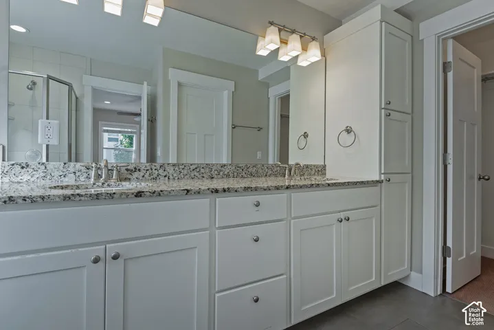 Dual vanity with white cabinetry, speckled countertop, and integrated sinks