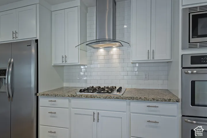Stainless steel appliances, white subway tile backsplash, white cabinetry, gas cooktop, and speckled countertops
