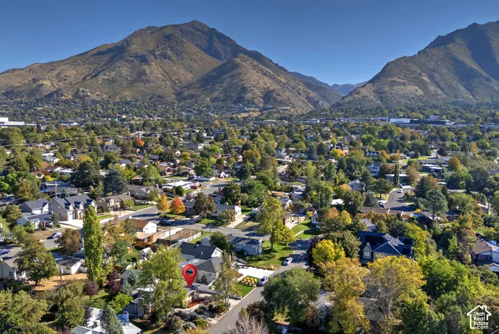 Expansive residential area with mature trees and varied architectural styles, set against a backdrop of distant mountains
