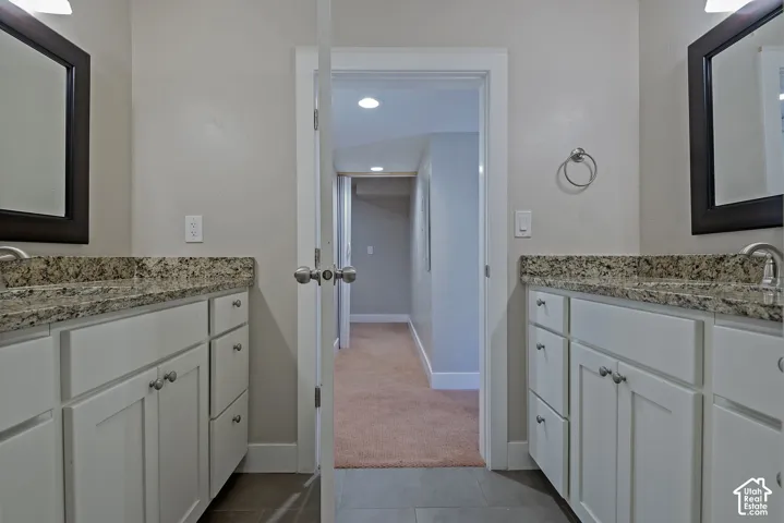 Dual vanity with white cabinetry, stone countertops, and dark framed mirrors