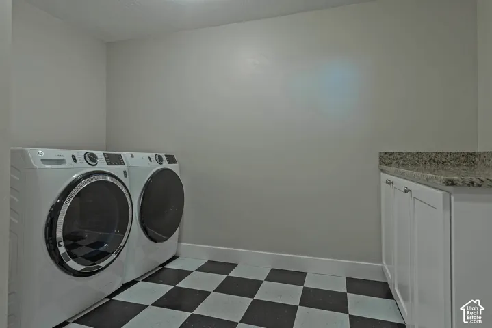 Checkered floor tiling, white baseboards, and built-in white cabinetry with a stone countertop