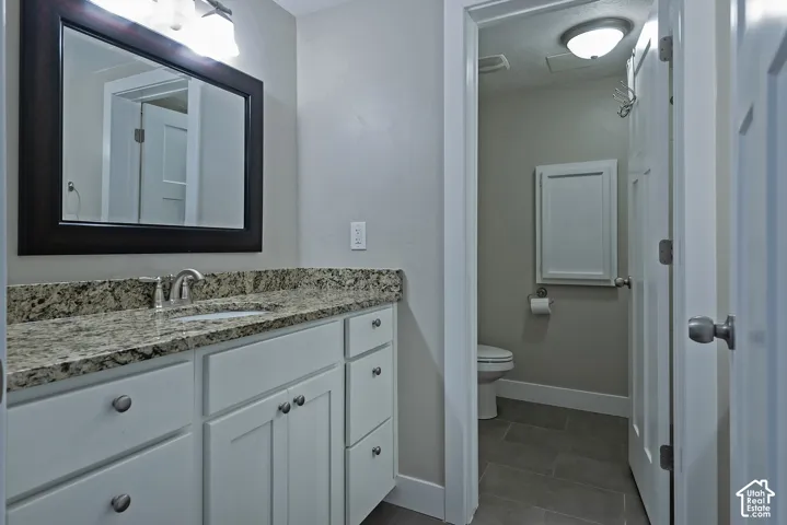 White shaker-style vanity with multiple drawers and cabinets, complemented by a speckled countertop