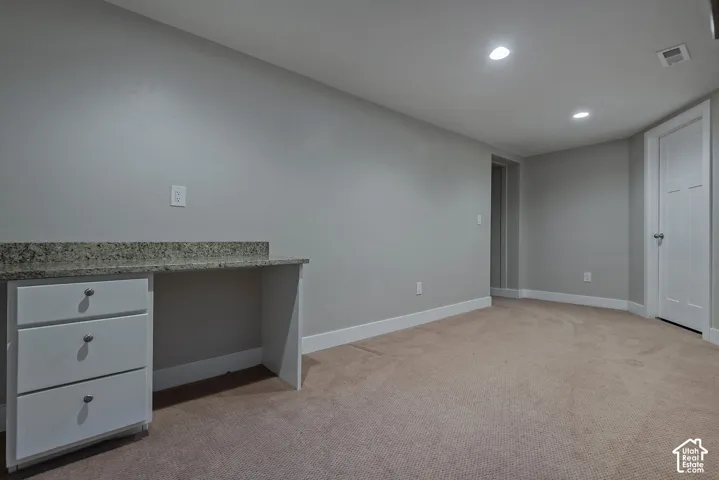 Built-in desk with a stone-finish countertop and white cabinetry
