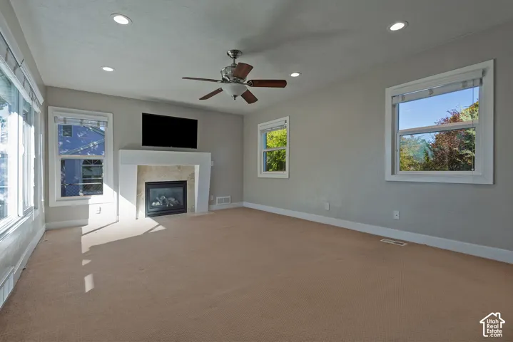 Recessed lighting, ceiling fan, carpeted flooring, fireplace with mantel, and multiple windows