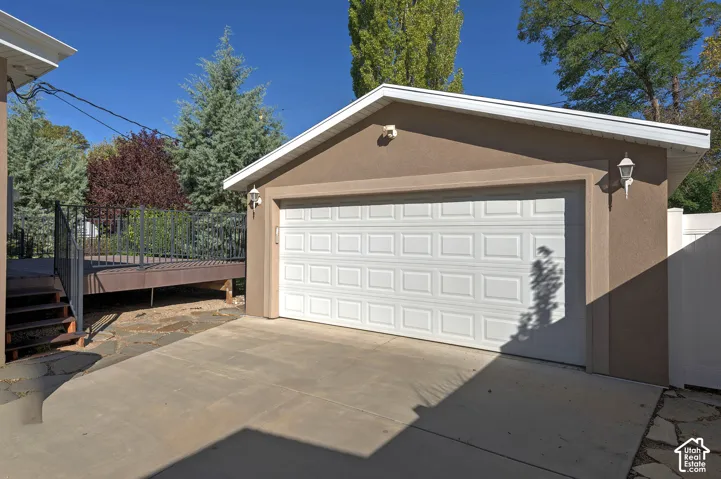 Attached garage with stucco exterior, a paneled garage door, and exterior wall-mounted lighting