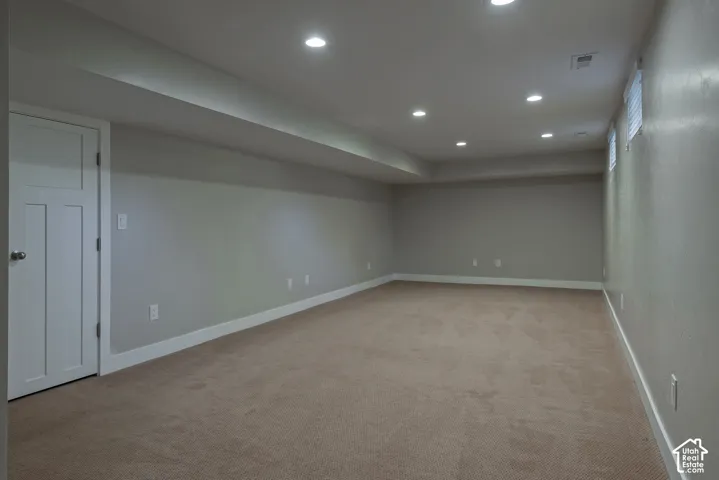 Neutral-toned carpeting, recessed lighting, and white trim throughout