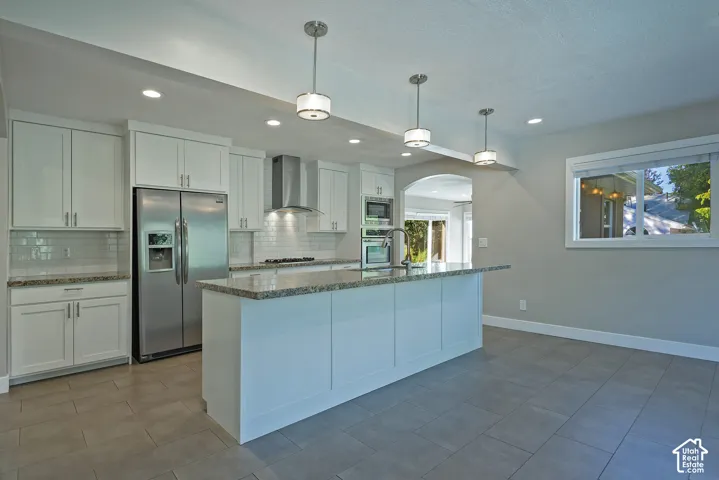 White cabinetry, stainless steel appliances, speckled stone countertops, tile flooring, and recessed lighting