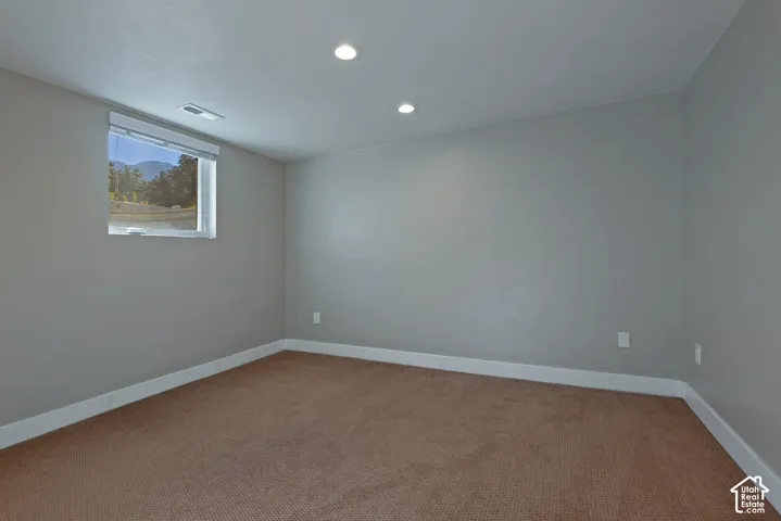 Recessed lighting, neutral wall paint, carpeted flooring, white trim, and a window with mountain scenery