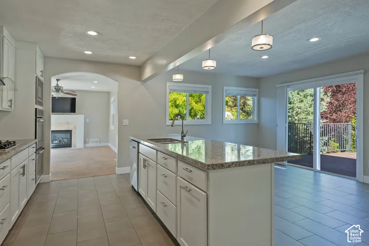Kitchen featuring white cabinetry, granite countertops, tile flooring, and stainless steel appliances