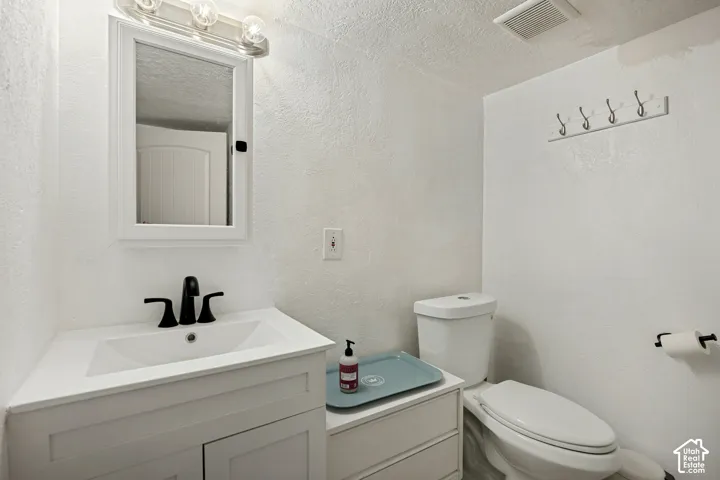 White vanity with integrated sink, black hardware, wall-mounted medicine cabinet, and three-bulb vanity light