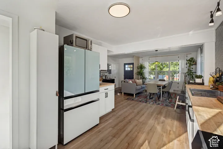 Wood-finish flooring, white cabinetry, light countertops, and a stainless steel sink with a matte black faucet