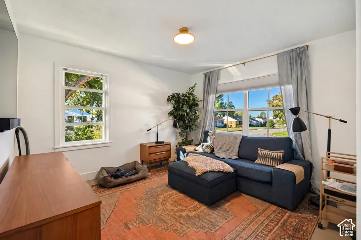 Bright living area featuring white walls, wood-finish flooring, and multiple windows providing natural illumination