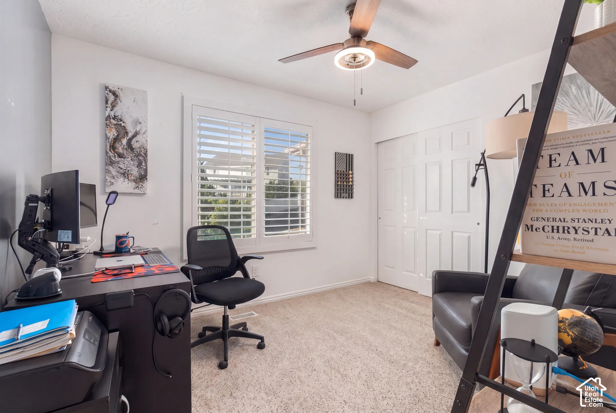 White window shutters, neutral carpeting, and a ceiling fan with integrated lighting