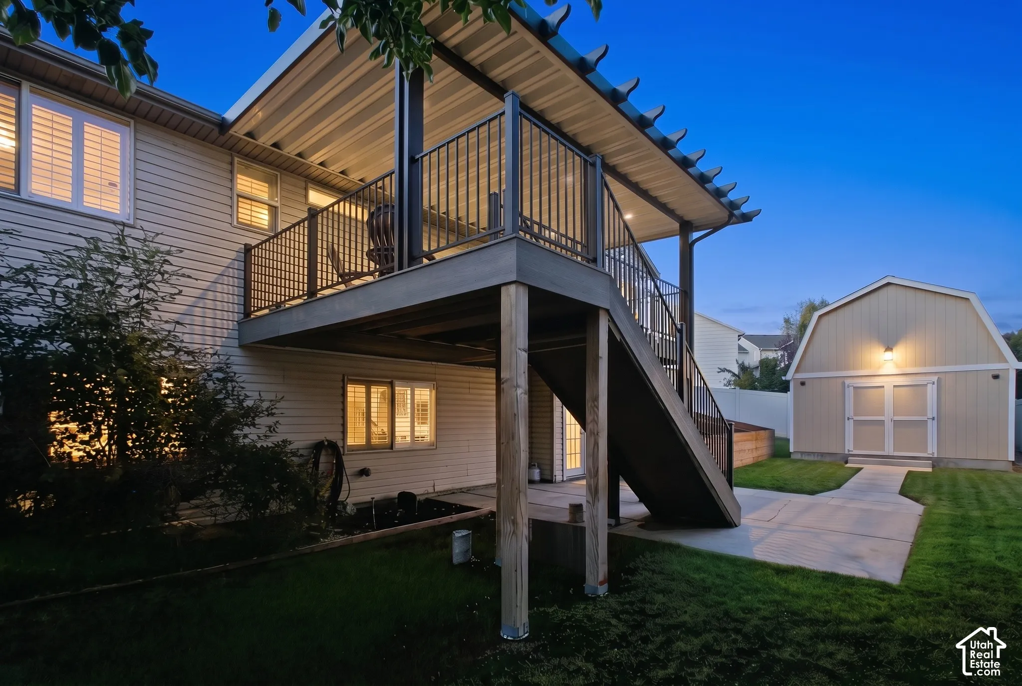 Expansive backyard featuring a multi-level deck, concrete patio, concrete pathway, and a detached shed with double doors