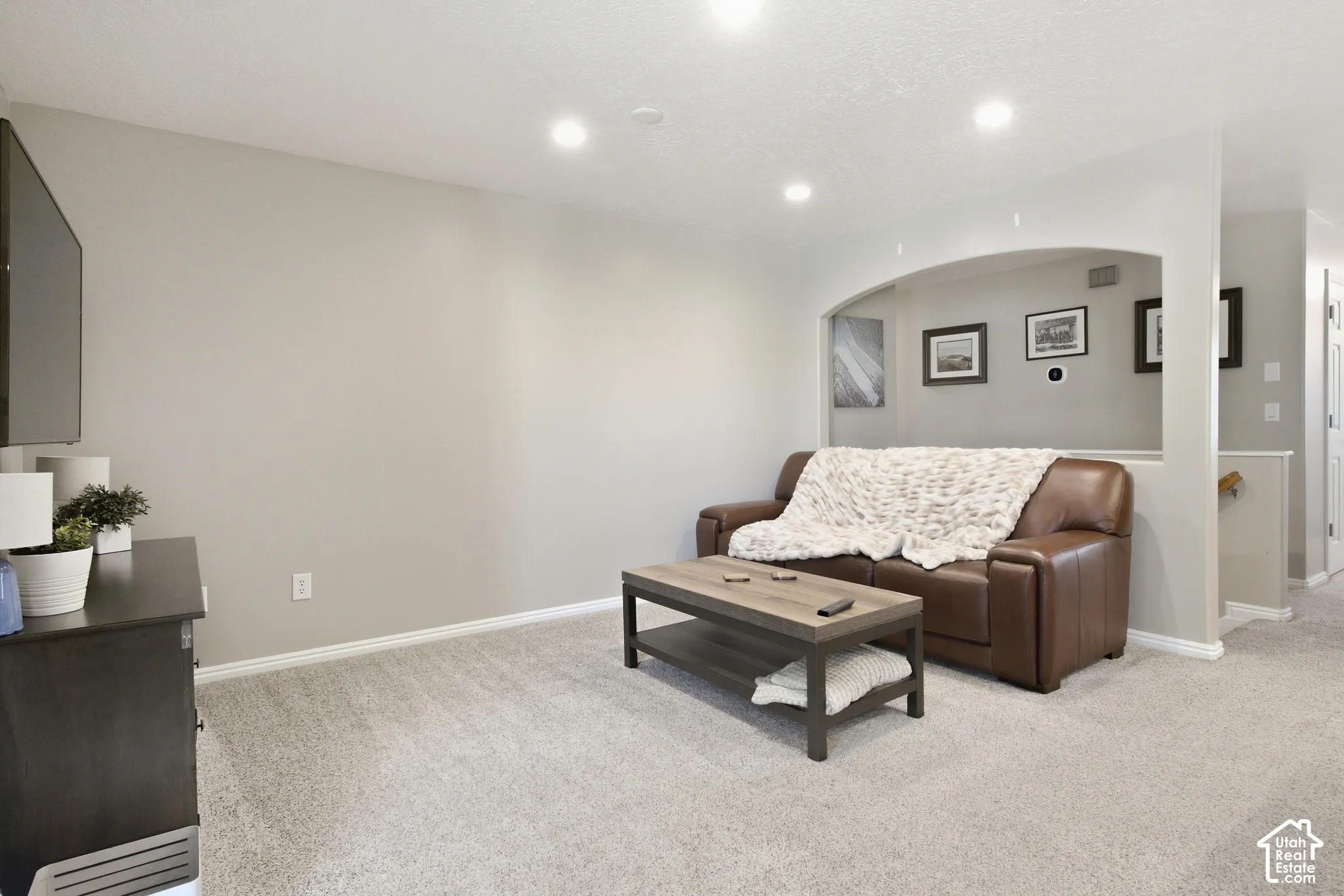 Recessed lighting fixtures, light neutral wall paint, light-colored carpeting, arched wall niche, and white trim