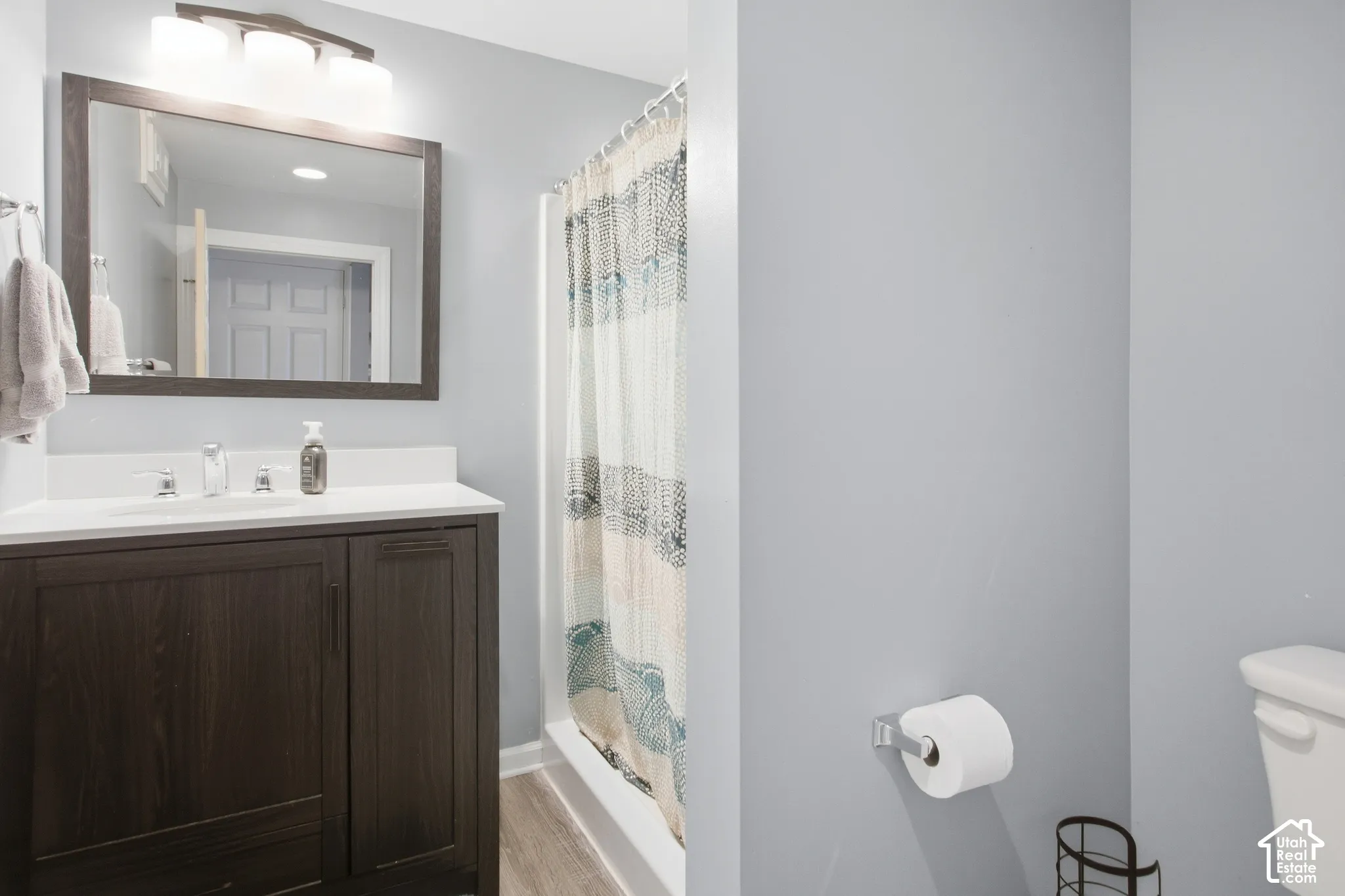 Wood-finish vanity with a white countertop and rectangular sink