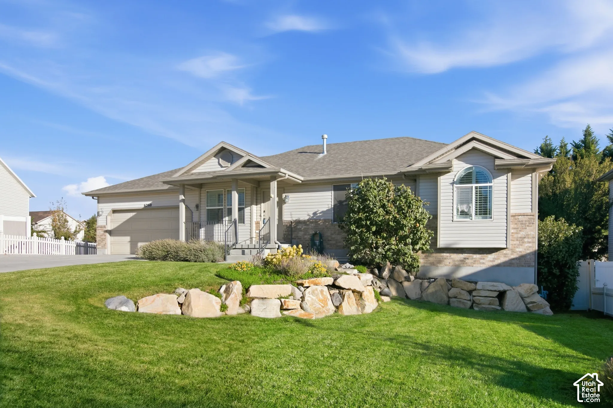 Exterior featuring a stone and siding facade, covered entry, attached garage, and arched window