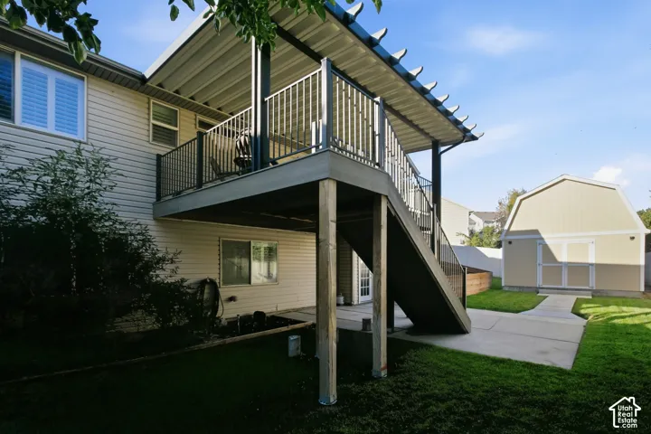 Covered second-story deck with metal railings and staircase, leading to a concrete patio