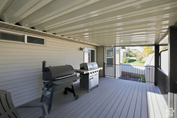 Covered deck featuring composite decking, metal railings, and vinyl siding