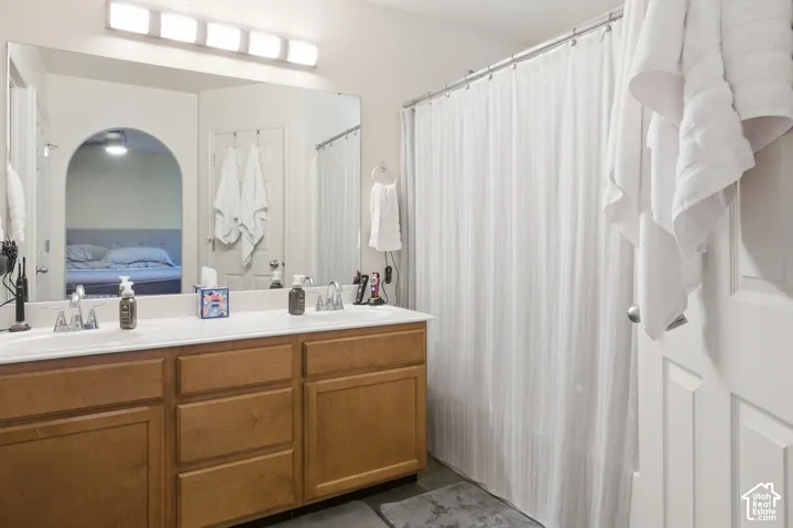 Double vanity with integrated sinks, wood-finish cabinetry, and a large wall-mounted mirror