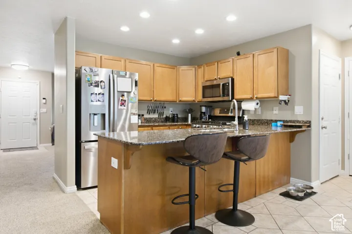 Kitchen featuring wood-finish cabinetry, stainless steel appliances, granite countertops, and recessed lighting