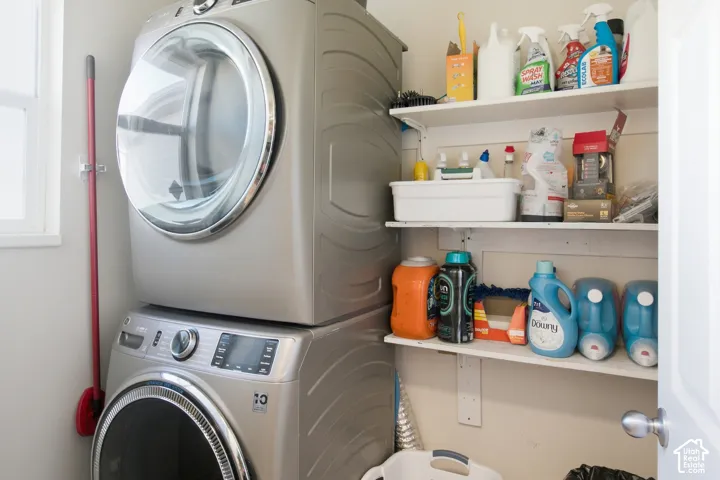 Stackable laundry appliances with a front-loading washer and dryer, featuring a white window and wall-mounted shelving