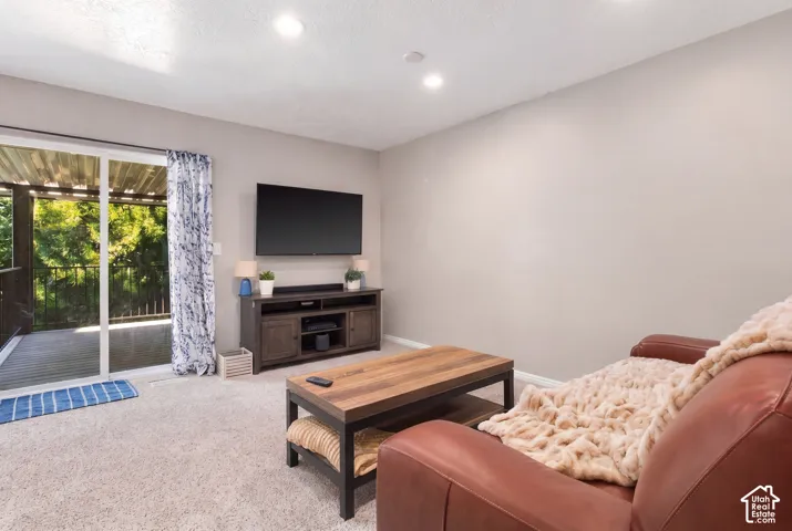 Recessed ceiling lighting, carpeted flooring, and a sliding glass door leading to an outdoor deck