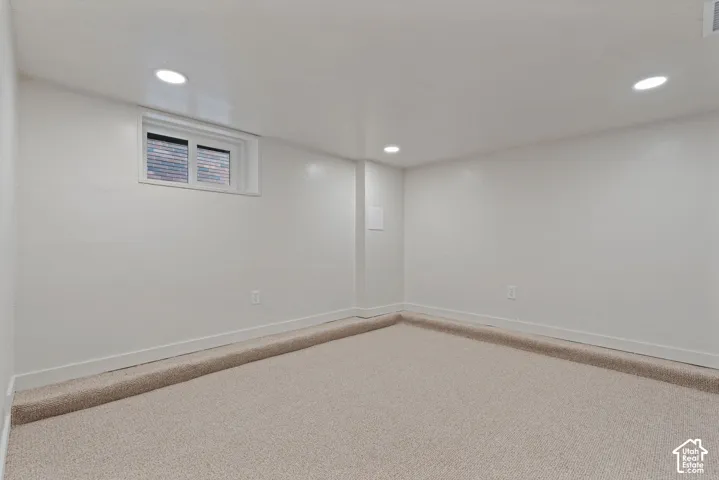 Recessed lighting fixtures, neutral wall color, window with horizontal blinds, and light-toned carpet flooring