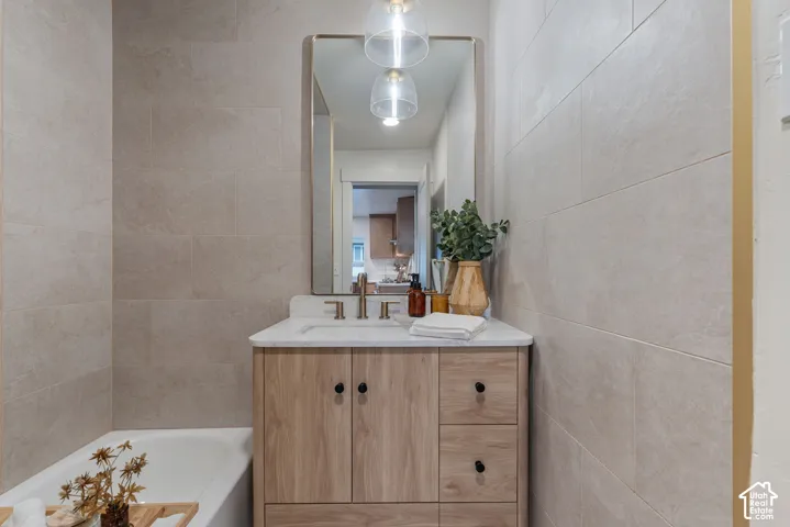 Light-toned tile walls surround a wood-finish vanity with a white countertop