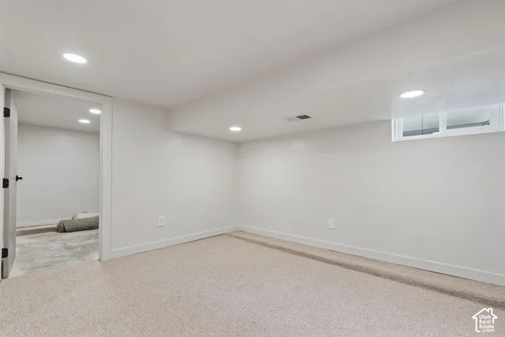 Recessed ceiling lighting, light-toned carpeting, white painted walls, and a window well