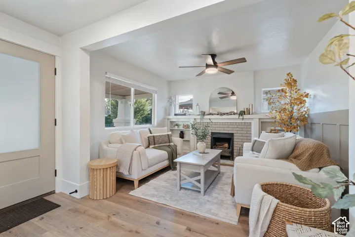 Wood-finish flooring, recessed lighting, ceiling fan, brick-surround fireplace, and wainscoting