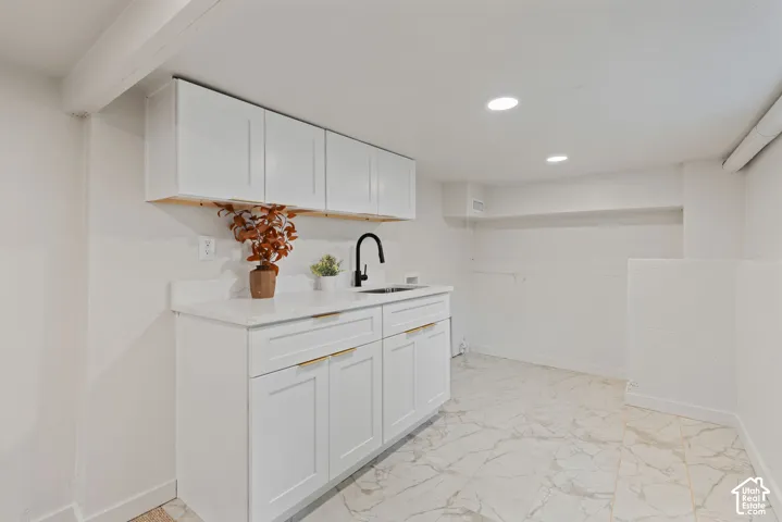 White shaker cabinetry with gold-tone hardware, white countertop, matte black faucet, undermount sink, and recessed lighting