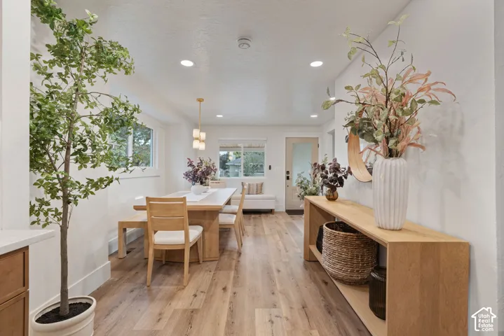Recessed ceiling lighting, wood-finish flooring, white walls, and a contemporary chandelier