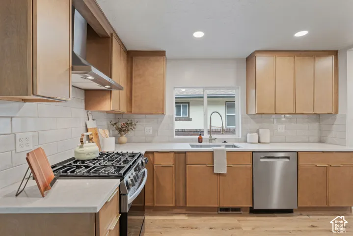 Kitchen featuring wood-finish cabinetry, white countertops, subway tile backsplash, stainless steel appliances, and wood-finish flooring